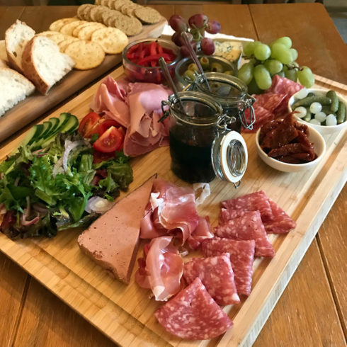 Picture of wooden board with cheese, crackers and cured meat