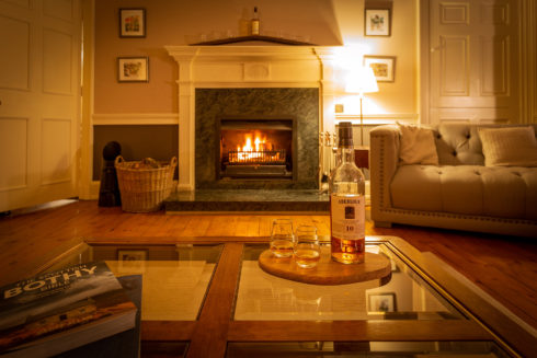 Inside view of the Drawing room's fireplace, coffee table and bottle and glasses of whisky