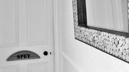 Black and white detail picture of Craigellachie lodge hallway with mirror and Spey room door