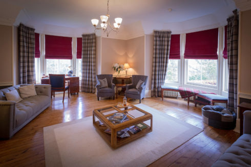 Inside view of the Drawing room, sofas, desk, coffee table and large window with view on the garden